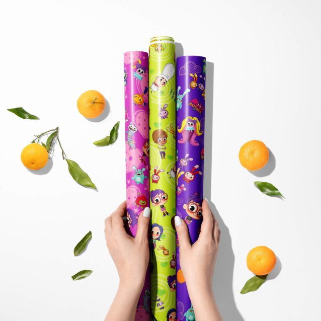 Unrolling a sheet of Abby Hatcher wrapping paper with colorful Fuzzly print.