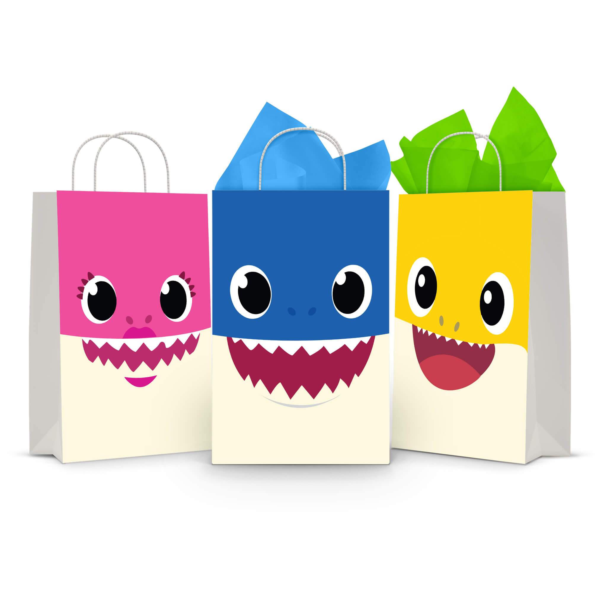 Three printable Baby Shark goodie bag fronts on paper party bags — the big-face designs for Mommy Shark on pink, Daddy Shark on blue and Baby Shark on yellow, mouths wide open.