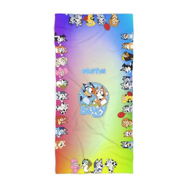 Draped over a rail, this colorful Bluey and Bingo beach towel shows the playful print in bright summer shades.