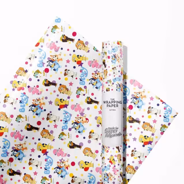 Action shot of kids excitedly unwrapping a gift covered in Bluey wrapping paper.