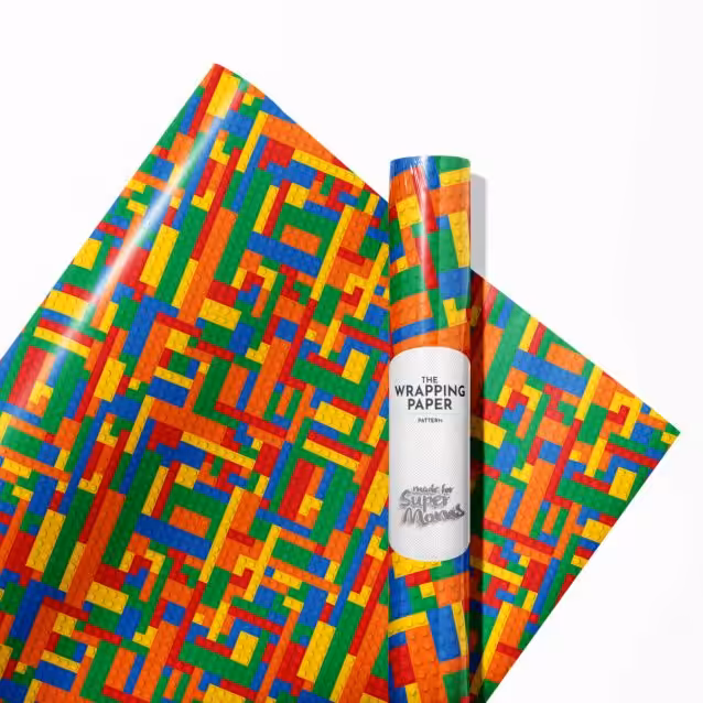 Child happily unwrapping a gift covered in Lego wrapping paper.