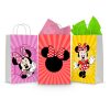 Three printable Minnie Mouse goodie bag fronts on paper party bags — Minnie in her pink polka-dot bow on lilac, the classic Minnie ears-and-bow silhouette on red, and Minnie waving on yellow.