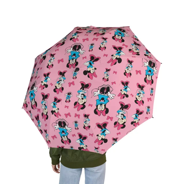 A woman smiling and holding the open Minnie Mouse umbrella in the rain.