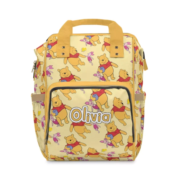 Soft yellow Winnie the Pooh diaper bag backpack covered in classic Pooh honey-pot art, personalized with the baby's name on the front pocket.