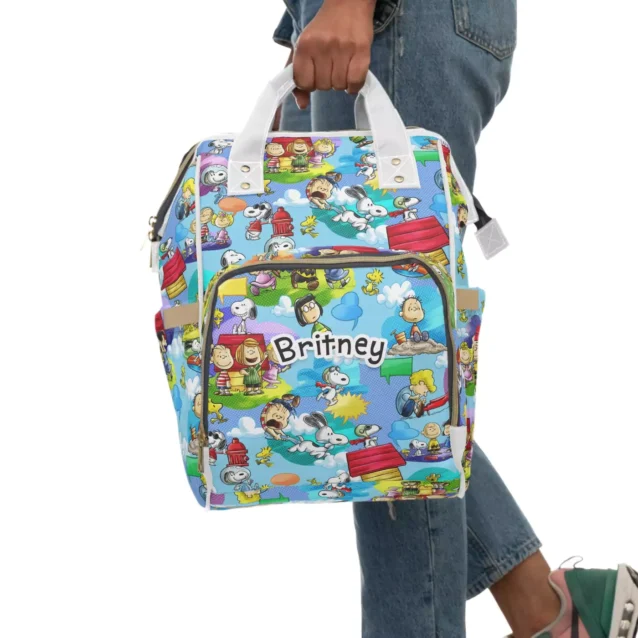 Snoopy diaper bag held by the top handles, personalized with the baby's name.