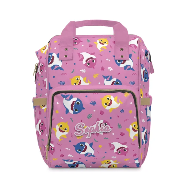 Pink Baby Shark diaper bag backpack with the shark family toss print, the baby's name printed on the front pocket.