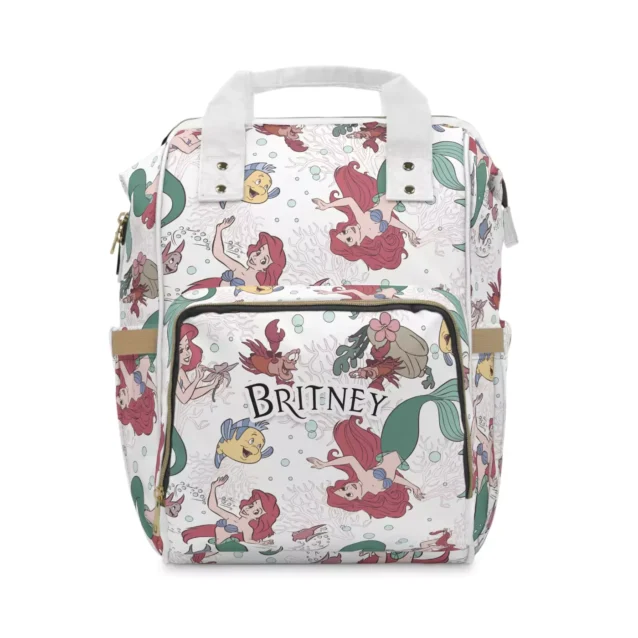 White Little Mermaid diaper bag backpack with a watercolor collage of Ariel and Flounder, the baby's name printed on the front pocket.