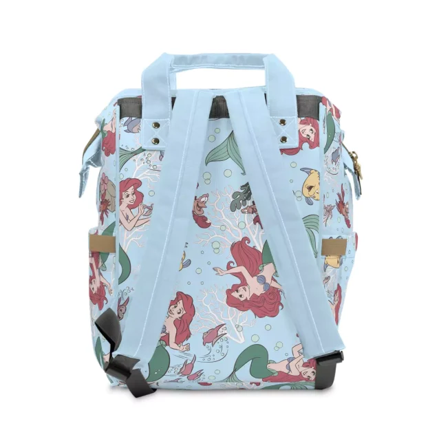 A lifestyle image of the Little Mermaid diaper bag at a park.
