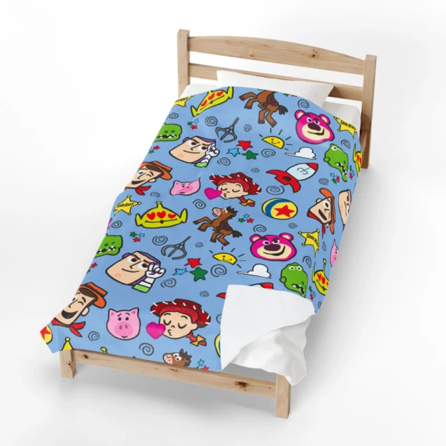 Toy Story fleece blanket in the Blue Cartoon Doodle design, spread on a kids bed.