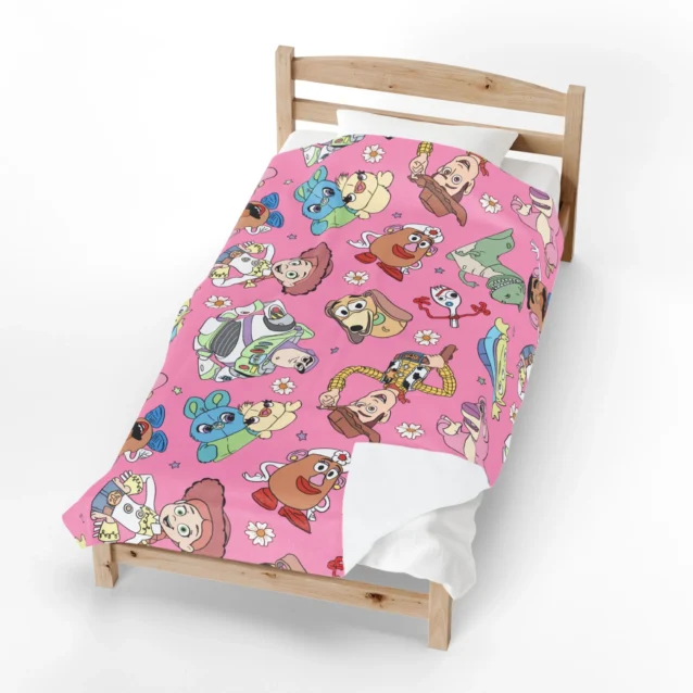 Toy Story fleece blanket in the Pink Character Print design, spread on a kids bed.